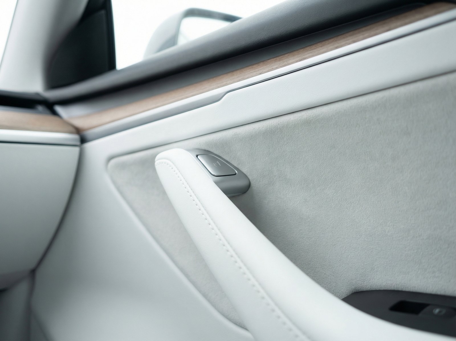 Close up of a Tesla Model 3 interior door panel showing the electronic button and hidden mechanical release, clean photography, modern automotive interior, soft natural lighting, 4:3