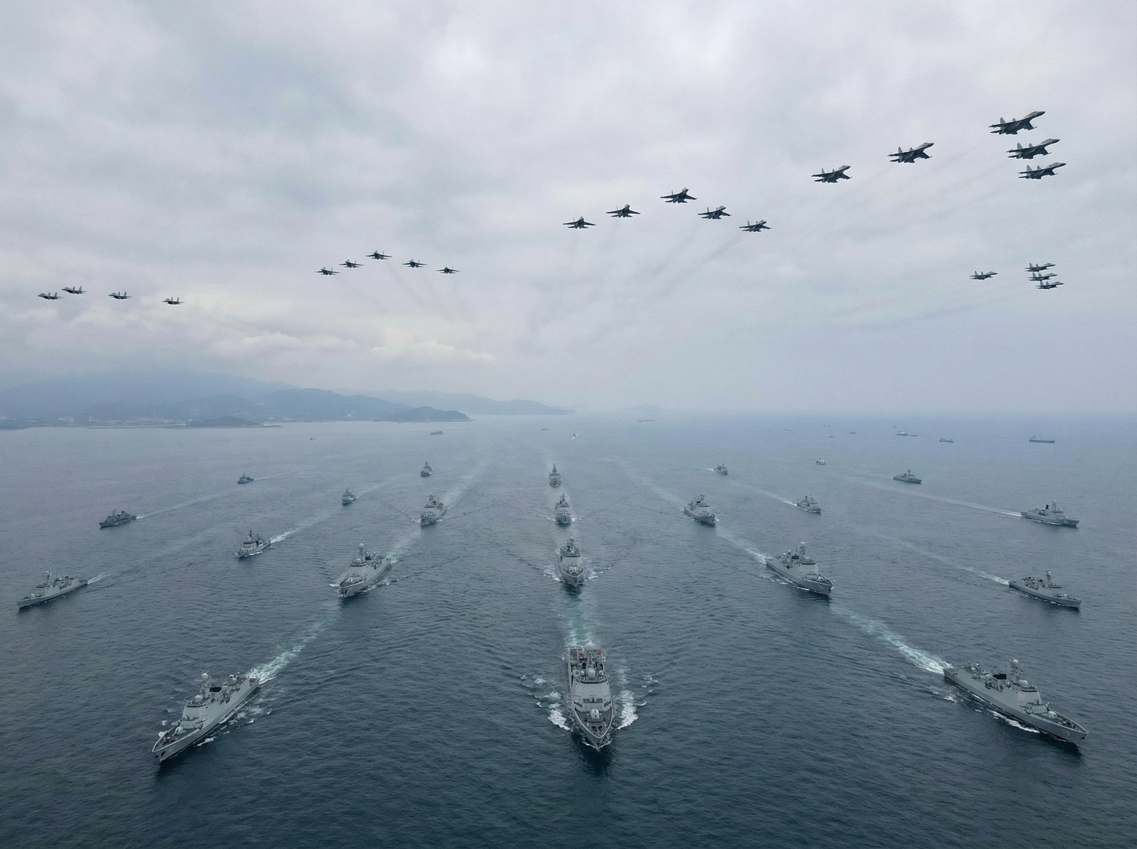 Chinese warships and fighter jets actively encircling Taiwan, illustrating the scale and intensity of the "Justice Mission 2025" drills. The image should convey a sense of a large-scale military exercise with multiple naval and aerial assets. Informational style, 4:3 aspect ratio, no visible text.