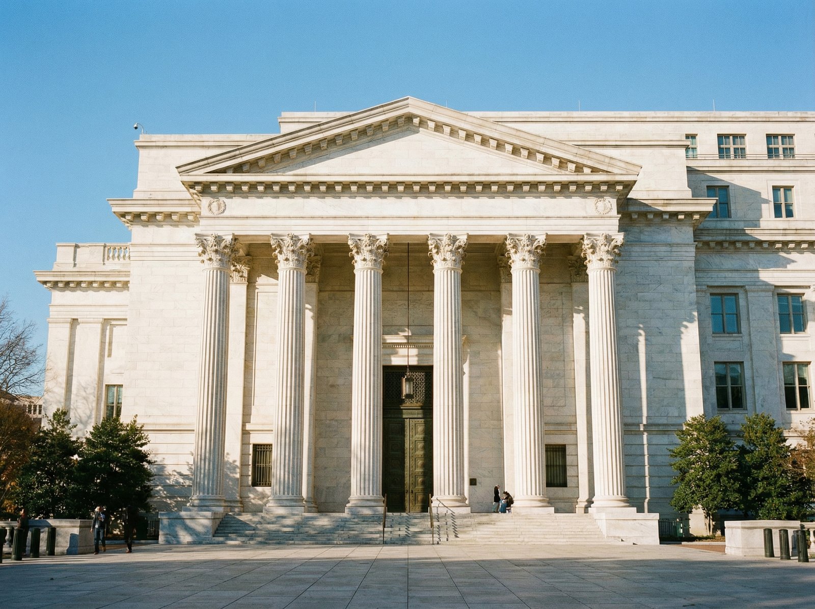 The exterior of the Federal Reserve building in Washington D.C., a grand and imposing structure. Focus on the classical architecture. Sunny day, clear sky. No visible text, 4:3 aspect ratio.