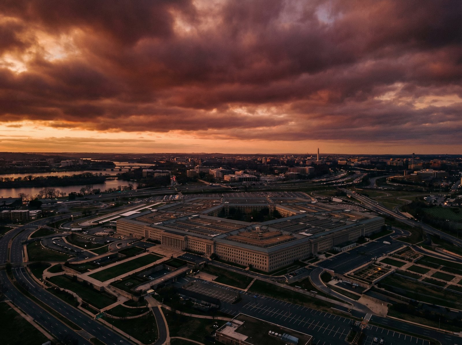 A professional high-angle shot of the Pentagon building in Arlington, Virginia, with a dramatic sky at sunrise, conveying a serious and official atmosphere, 4:3 aspect ratio, no text.