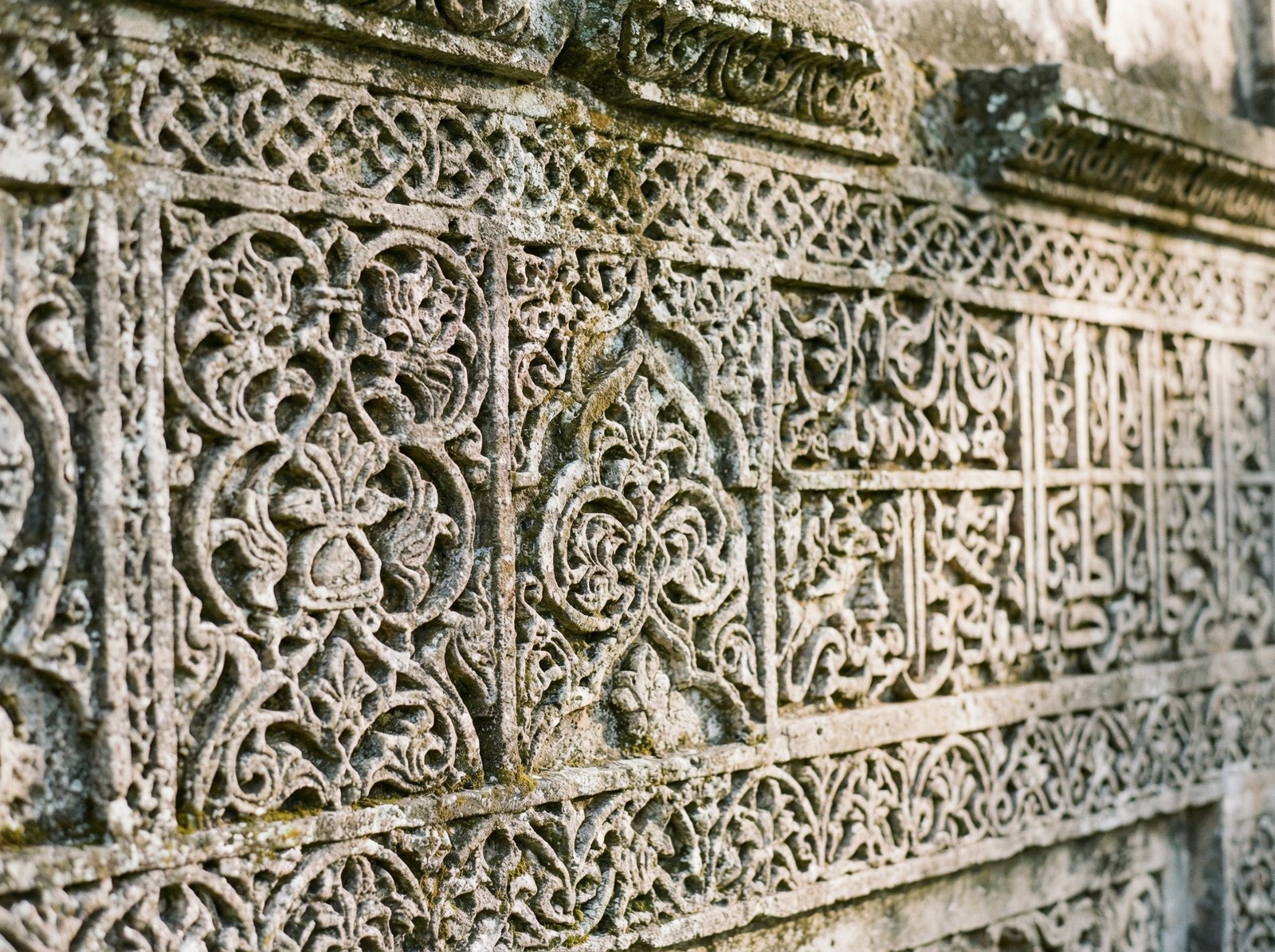 Close-up of intricate decorative carvings on a coral stone wall in Kilwa, showing Swahili architectural influence, soft natural lighting, 4:3 aspect ratio, no text