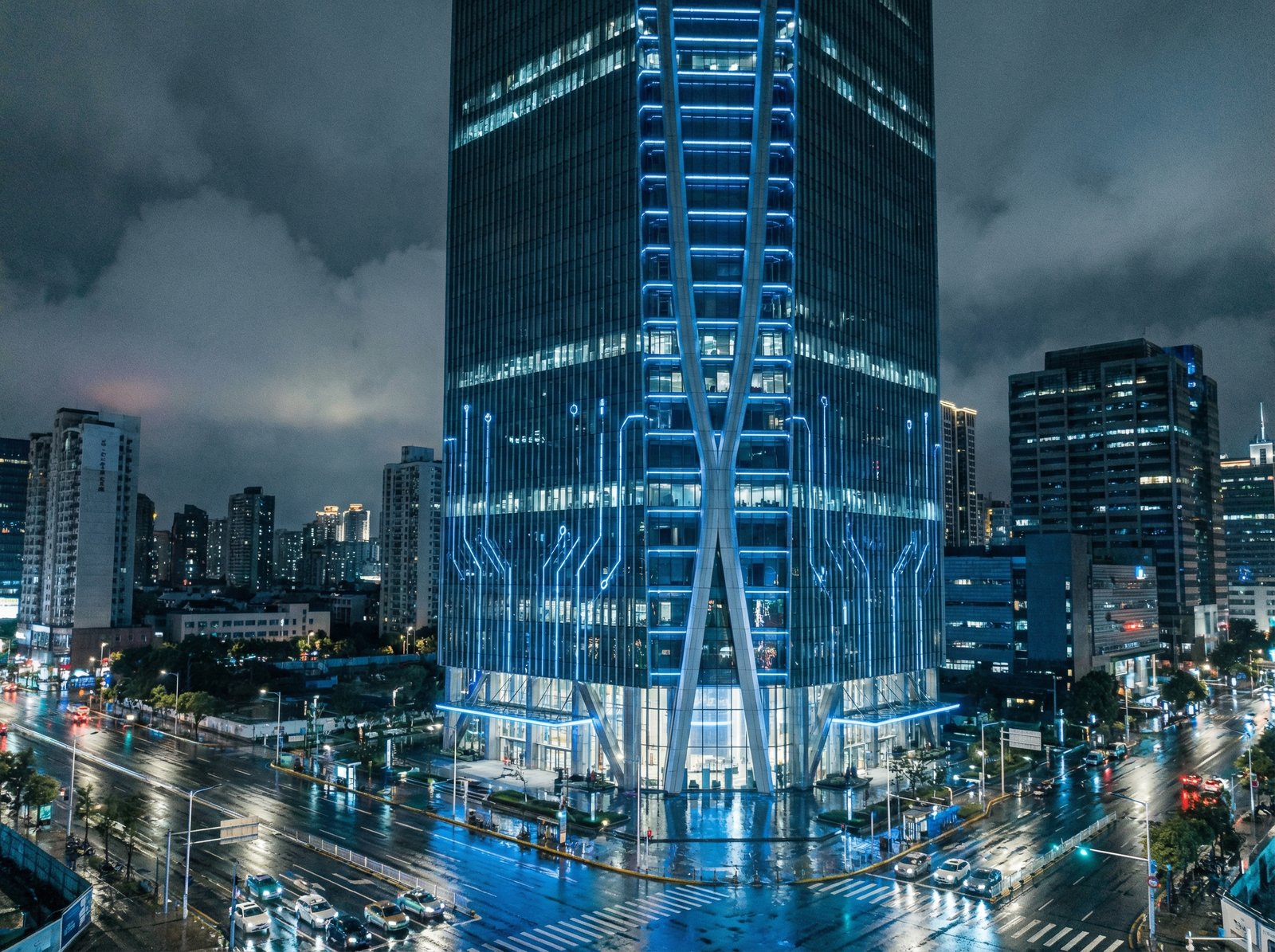 A high-tech skyscraper building with a subtle blue glow at night, representing a global electronics company headquarters, sleek modern architecture, cinematic lighting, 4:3 aspect ratio, no text.