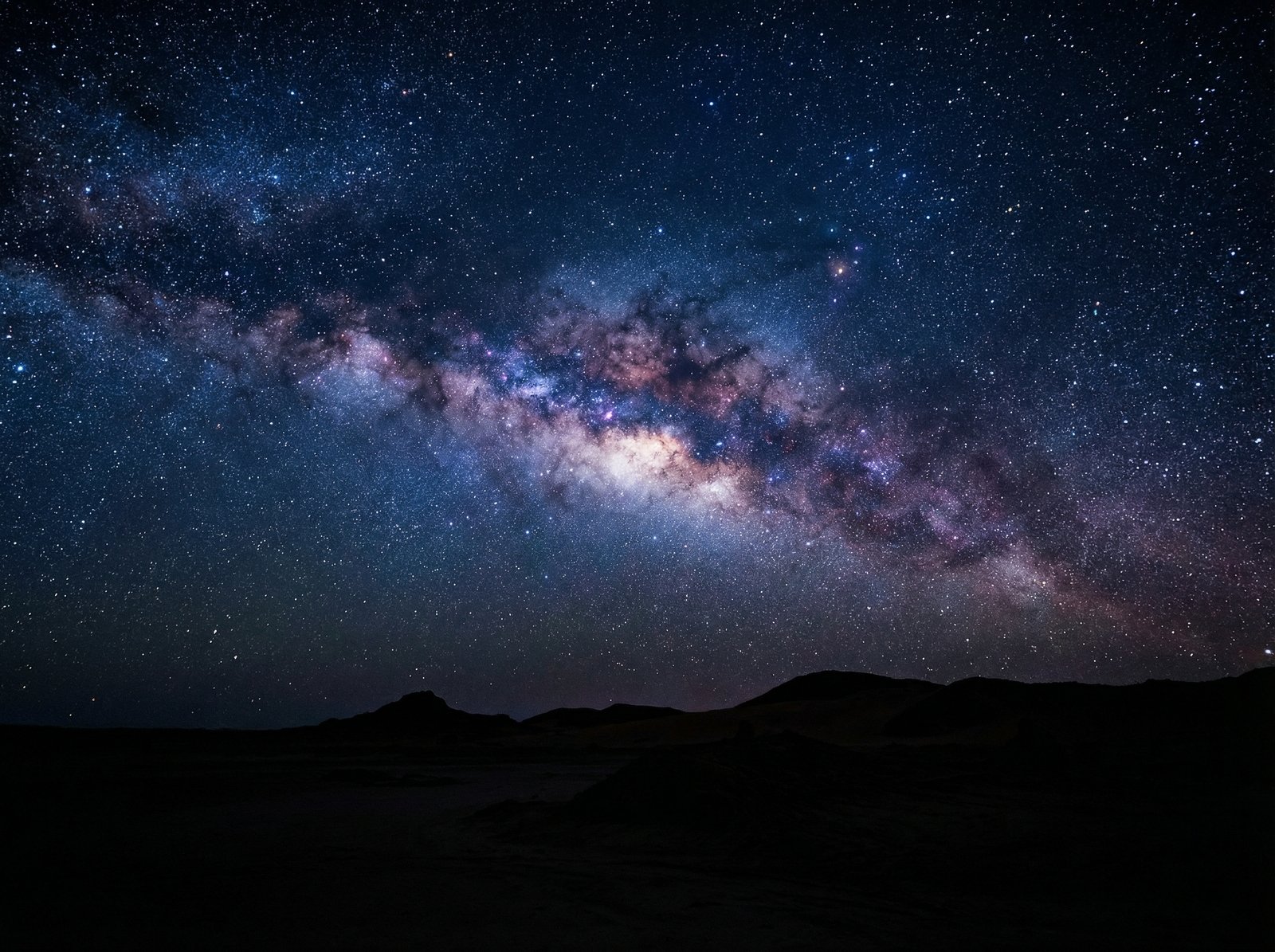 Vibrant Milky Way galaxy stretching across a dark night sky over the silhouetted desert landscape of Willandra Lakes, deep blue and purple hues, thousands of stars, high contrast, 4:3, no text