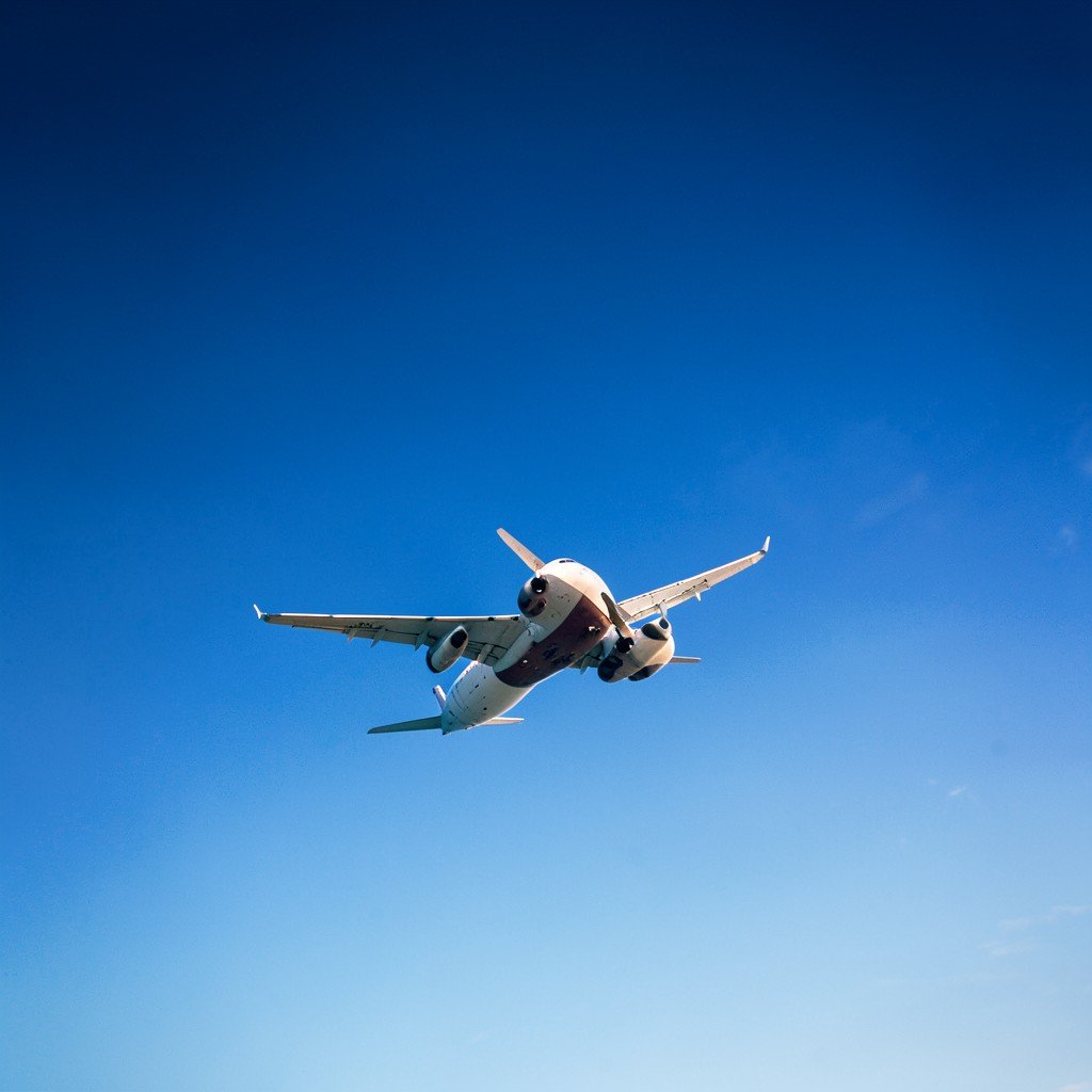 An airplane flying through a clear blue sky, wide angle shot, high altitude, professional travel photography, 4:3.