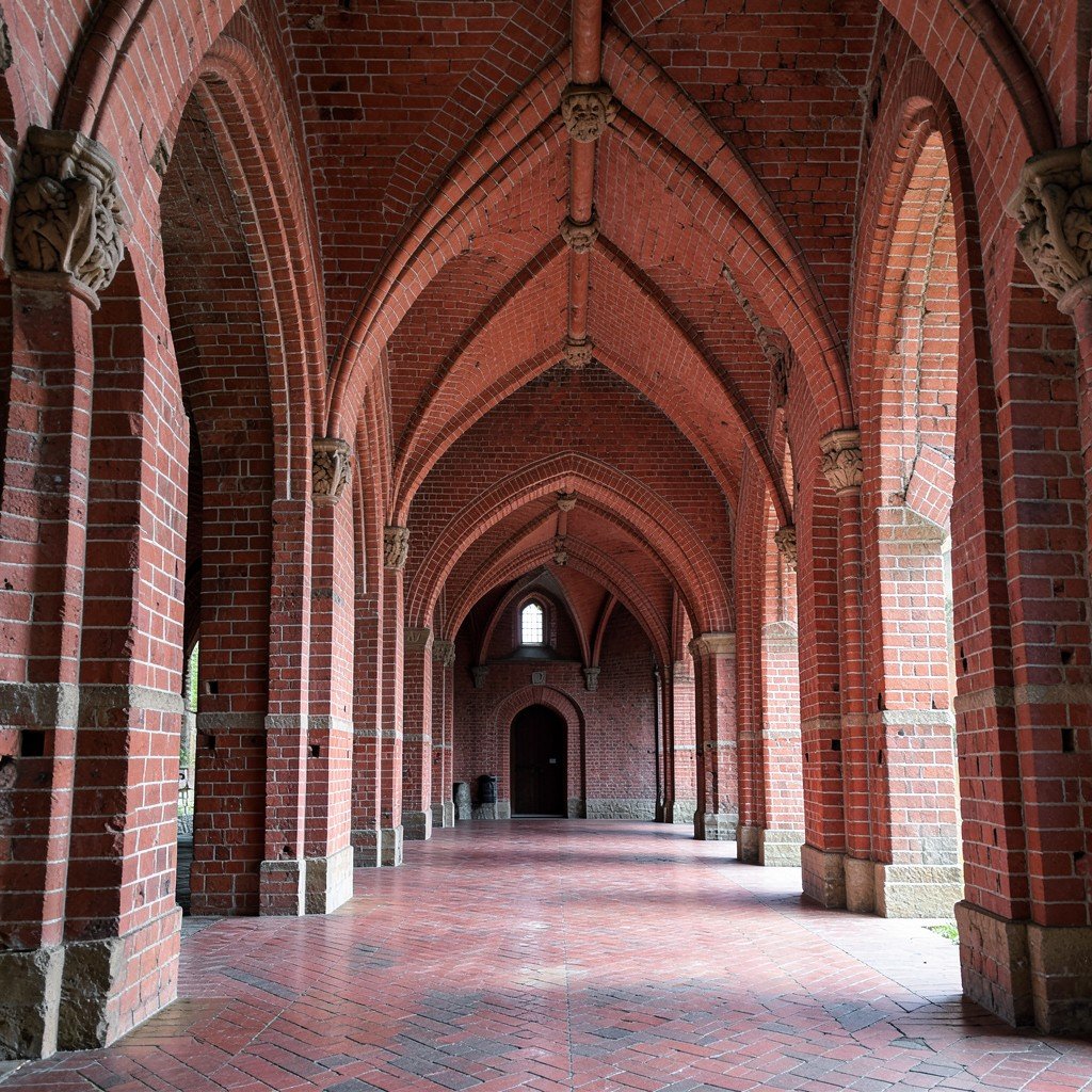 Interior cloister and red-brick corridors of Malbork Castle in Poland, medieval Gothic arches, soft daylight, no visible text, no logos, no watermark, aspect ratio 1:1
