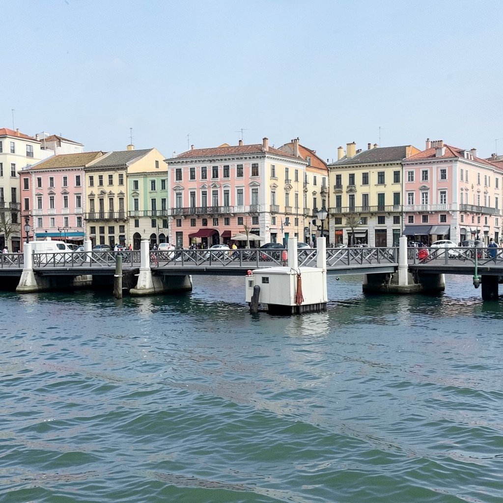 Queen Emma pontoon bridge floating across the harbor channel in Willemstad, pastel historic waterfront buildings in background, gentle sea waves, no visible text, no logos, no watermark, aspect ratio 4:3