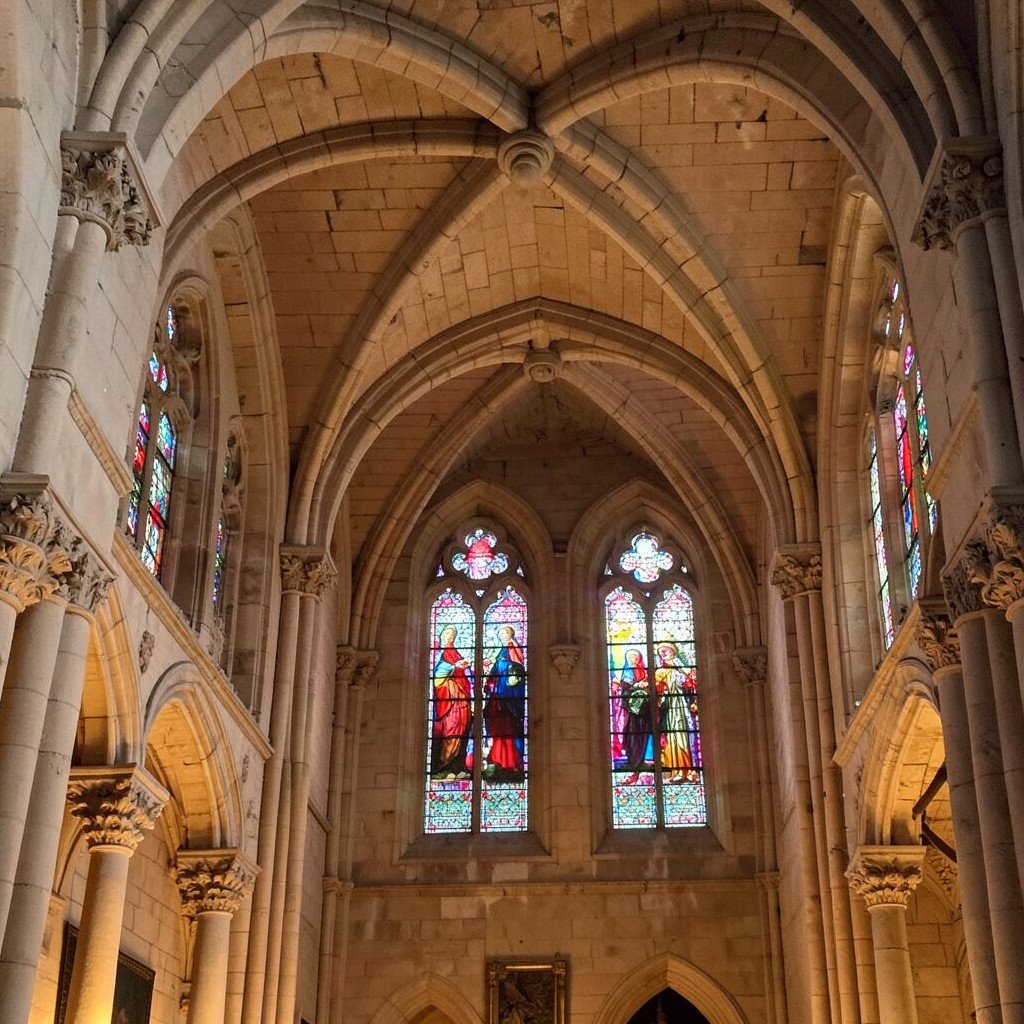 Interior of the Basilica of Saints Nazarius and Celsus in Carcassonne featuring colorful Gothic stained glass windows and stone vaulted arches, warm interior light, no visible text, no logos, no watermark, aspect ratio 1:1